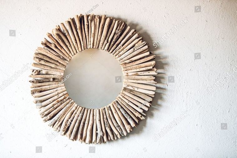 A driftwood sunburst mirror on a white plaster wall